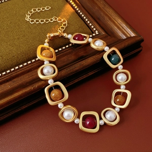 Détail d'un bracelet vintage doré avec perles colorées sur un fond en cuir brun