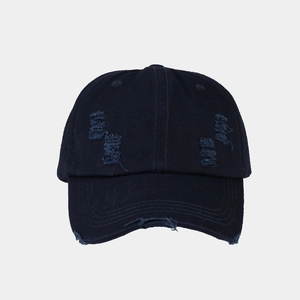 Close-up of washed navy blue baseball cap featuring distressed holes and frayed edge details