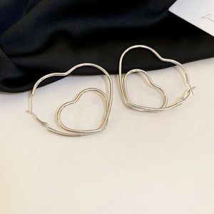 Dettaglio di orecchini a doppio cuore su un elegante sfondo in tessuto di seta nera
