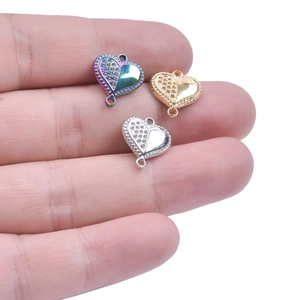 Stainless steel heart connectors in gold, silver, and rainbow finishes on a palm