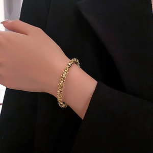 Close-up of minimalist adjustable golden woven metal bracelet on a female wrist