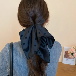 Dettaglio di un grande fermaglio per capelli a fiocco a pois neri su coda bassa