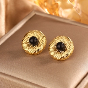 Macro shot of gold spiral weave earrings with black beads on a luxury velvet box