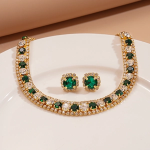 Detailed view of luxury gold necklace and earrings set with green and white crystals