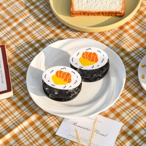 Detailed view of sushi-shaped acetate hair claws on a white plate with picnic props