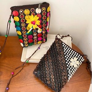 Detail view of Bohemian handmade seashell woven crossbody bags with flower accents