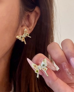Macro detail of butterfly stud earrings with colorful zircons on a model's ear
