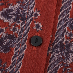 Close-up of ethnic print maxi dress fabric featuring red floral pattern and black button