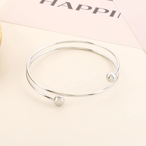 Detail of minimalist silver double-layer open bangle with polished spherical ends