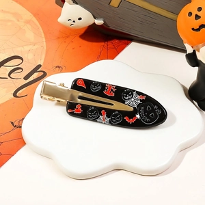 Halloween duckbill hair clip with pumpkin and bat motifs on a white cloud tray