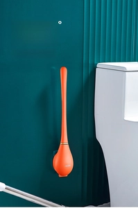 Détail de la brosse de toilette murale orange avec crochet sur mur vert