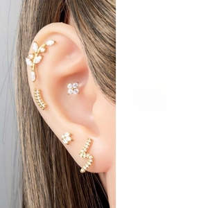 Close-up of gold ear piercing set with leaf and flower studs featuring white cubic zirconia