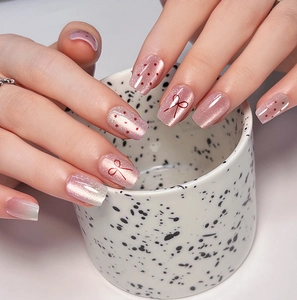 Close-up of pink cat eye nails with red polka dots and bow designs on short square shape