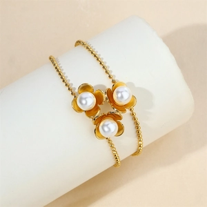 Elegant gold flower bracelet with pearls wrapped on a cylindrical white display stand