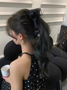 Detail of a black double-layered mesh bow banana clip worn on a high ponytail