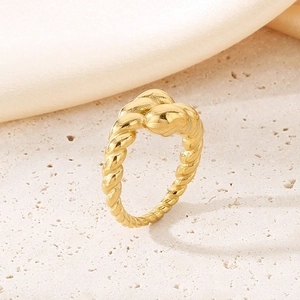 Macro shot of 18K gold plated twisted rope ring design on light stone base