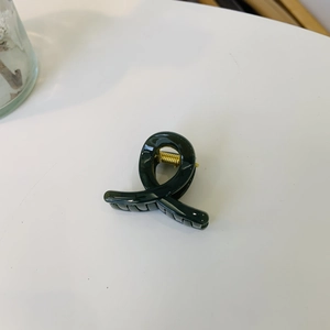 Close-up of a glossy dark green shark hair claw clip with a strong gold metal spring