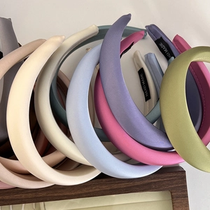 Close-up of colorful handmade padded satin headbands in beige, purple and green colors