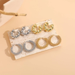 Detailed close-up of twisted and beaded hoop earrings in gold and silver finishes