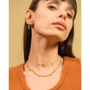 Detail of 18K gold-plated necklace with emerald green zircon stones on professional model