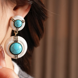 Close-up of vintage resin round earrings with turquoise center and crystal accents