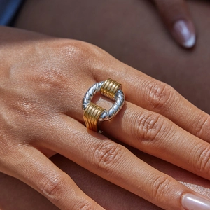 Détail d'une bague bicolore en acier inoxydable avec texture torsadée et accents dorés