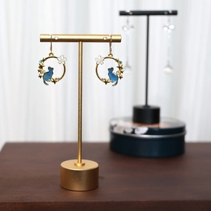 Golden cat earrings with blue star and floral accents on a minimalist T-bar display stand