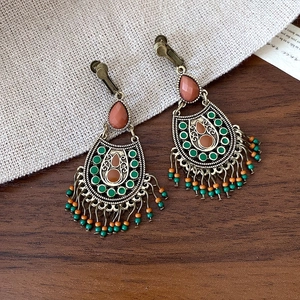 Macro shot of vintage bohemian bronze teardrop earrings with colorful beads and gemstones