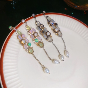 Detailed shot of vintage earrings with colorful gemstones and hanging water drop pearls