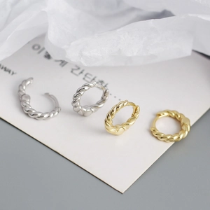 Detail of twisted rope style hoop earrings in silver and gold metal finishes