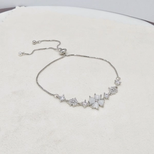 Detailed macro view of silver clover bracelet with white cat-eye stones and adjustable slide clasp