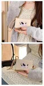Close-up of beige wallet with dachshund dog embroidery and matching wrist strap