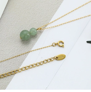 Macro detail of 18K gold chain with green jade gourd pendant and K18 hallmark stamp