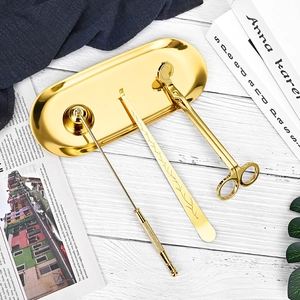 Kit d'accessoires de bougie doré avec coupe-mèche et éteignoir sur un plateau