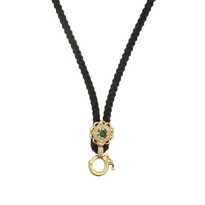 Close-up of a black braided necklace featuring a gold flower pendant with green gemstone