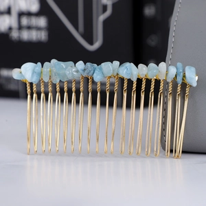 Dettaglio macro di cristalli azzurri avvolti a mano su un pettine per capelli dorato