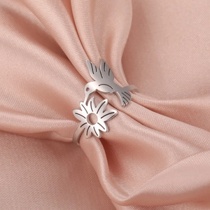 Macro shot of silver hummingbird and flower ring on elegant pink silk fabric