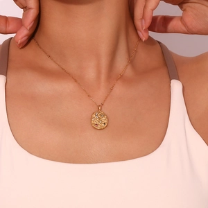 Detail of 18K gold-plated oval pendant with moon and star motifs on a delicate chain