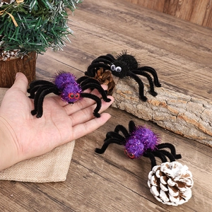 Halloween plush spider hair clips in purple and black colors shown on a hand