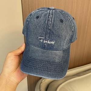 Detailed close-up of blue denim baseball cap featuring white Forever cursive embroidery