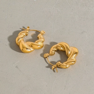 Macro shot of twisted 18k gold plated titanium steel earrings with high gloss finish