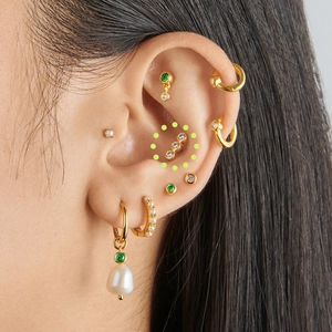 Detailed close-up of a gold s925 sterling silver curved cartilage stud with three zircons