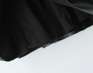 Detailed close-up of the black PU leather hemline with fine stitching and soft pleats