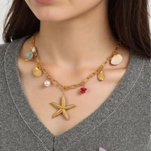 Gold ocean shell starfish charm necklace with pearls on a model wearing V-neck