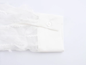 Detailed close-up of a white shirt cuff with textured fabric and single button fastener