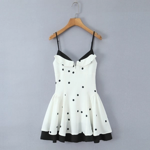 Détail d'une robe blanche à pois avec encolure à volants et fines bretelles réglables