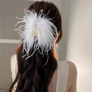 Detailed view of white ostrich feather hair claw clip on brunette hair for elegant styling