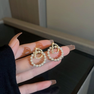 Vue macro de boucles d'oreilles perles avec lettre D en cristal et finition dorée