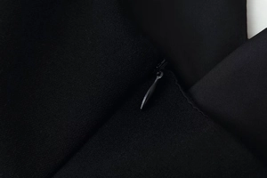 Detailed close-up of a concealed zipper and fabric texture on a slim-fit black dress