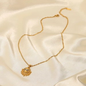 Détail du pendentif soleil plaqué or 18K avec zircon sur fond de soie couleur champagne doré